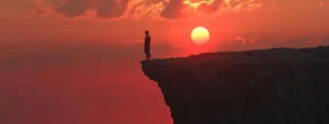 a person standing confidently at the top of a mountain, looking out at a breathtaking sunset, symbolizing their enhanced mental and physical health through psych-k.