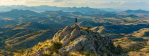 a person standing on top of a mountain peak, looking out at a vast and picturesque landscape, symbolizing the journey to success through the cultivation of positive habits.